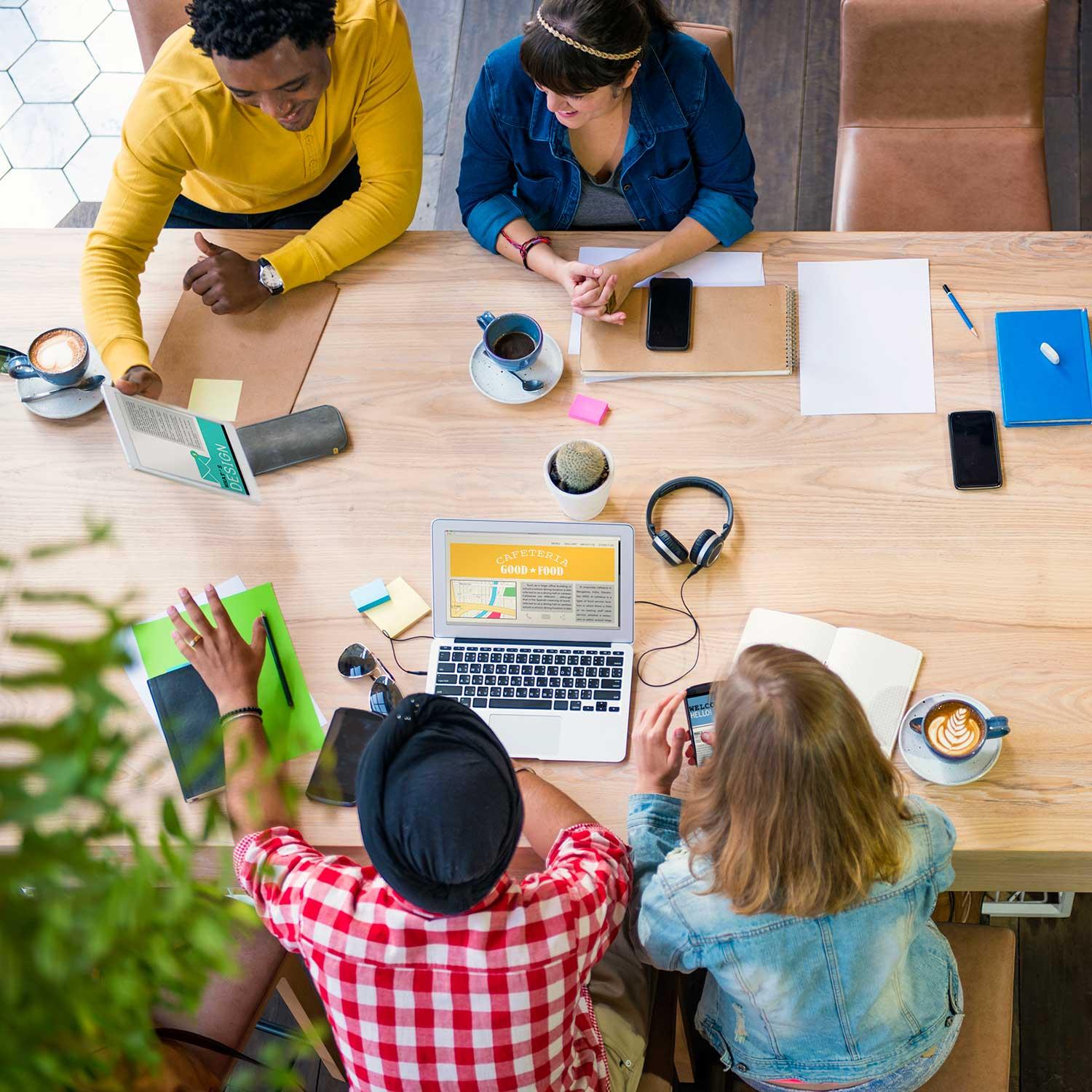 Diverse team collaborating around a table with laptops - WayRankPro digital marketing team portfolio